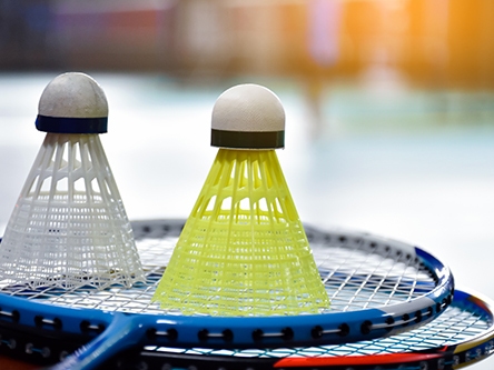 Volants de badminton en plastique blanc et jaune sur raquettes bleues