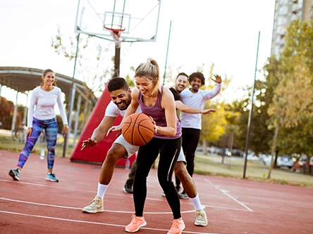 Groupe d'amis jouant au basket-ball sur un terrain extérieur