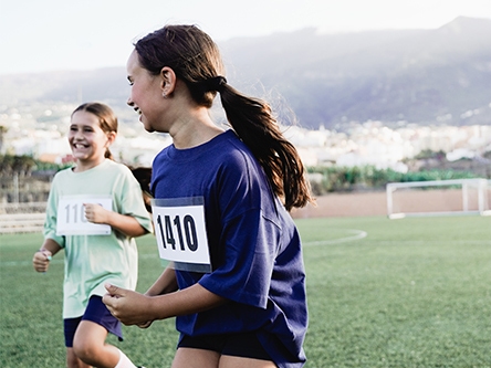 Deux jeunes filles courent avec des dossards sur un terrain de sport. Deux jeunes filles courent avec des dossards sur un terrain de sport.