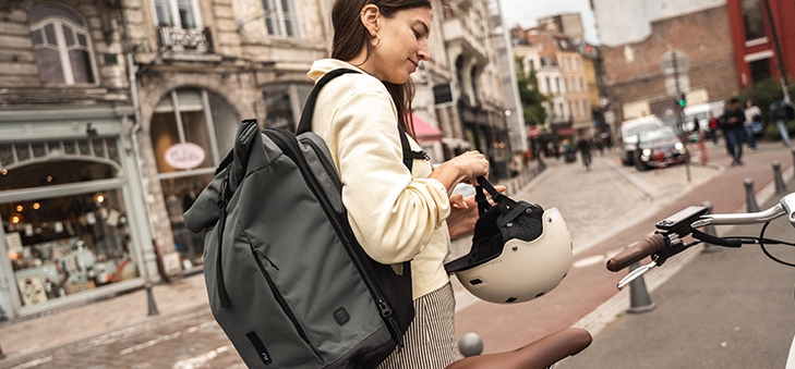 Une femme en ville attachant son casque à son vélo avant de partir au travail.